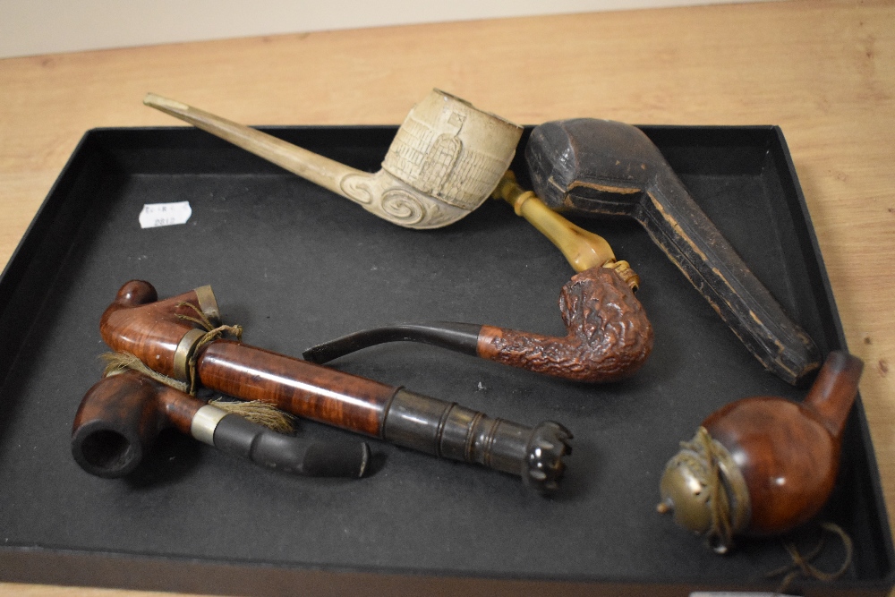 A collection of vintage and antique pipes, including large clay pipe with carved decoration, opium