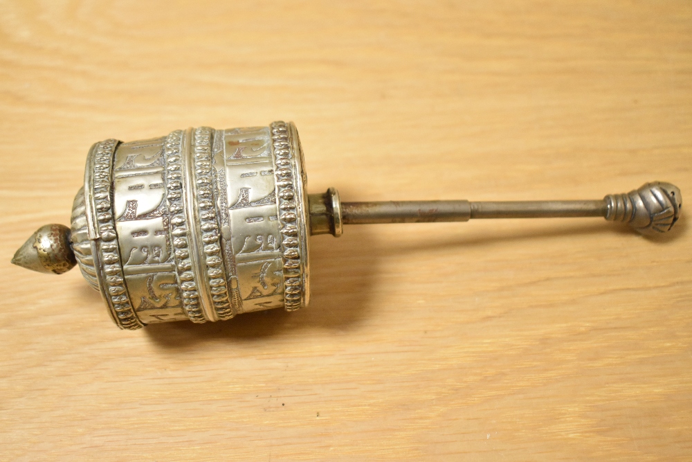 An antique white metal Tibetan prayer wheel, measuring 20cm, with engraved design