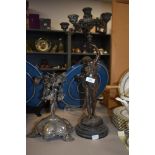 A 19th century cast patinated metal candlestick, with semi nude female to centre, sat on wooden
