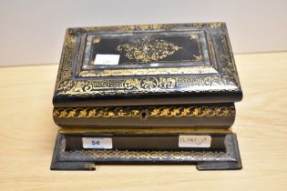 An early 19th Century black lacquered papier mache tea caddy, of sarcophagus form and decorated in