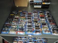 A shelf of Mattel Hot Wheels die-casts, 2002 period onwards, 70 in total, all on bubble display