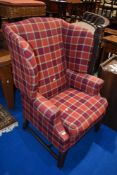 A traditional wing back arm chair in red check upholstery