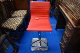 A modern kitchen bar stool, in chrome and red leather