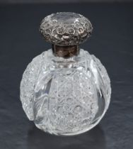 A late Victorian silver-topped glass scent bottle, the foliate embossed screw-off cover with loose