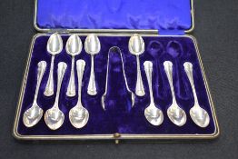 A part set of George V silver teaspoons and sugar tongs, each with scroll decoration to terminals,