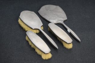 A George VI silver backed four piece brush set, comprising hand mirror, hair brush and two clothes