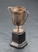 A George V silver trophy, of two-handled cylindrical form with short knopped stem and canted