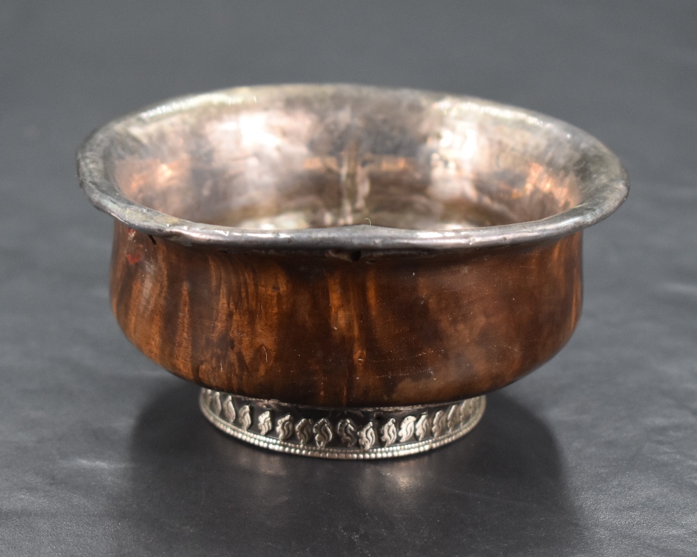 A 19th century Chinese/Tibetan white metal mounted Mazer bowl, of turned form with white metal