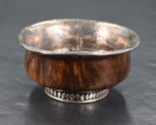 A 19th century Chinese/Tibetan white metal mounted Mazer bowl, of turned form with white metal