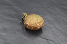 A small gilt metal coin holder, of hinged circular form with textured surface 3cm diameter.
