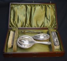 A George V silver backed five-piece dressing table brush set, comprising hand mirror, hair brush,