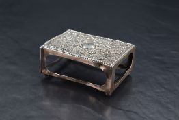 An Edwardian silver match box holder, of rectangular form, the top embossed with figures, flower