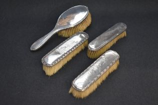 A group of four silver mounted brushes, comprising hair brush and three clothes brushes, two being