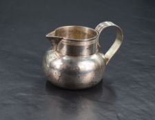 A George V silver cream jug, of flattened spherical form with short raised neck and sparrow beak