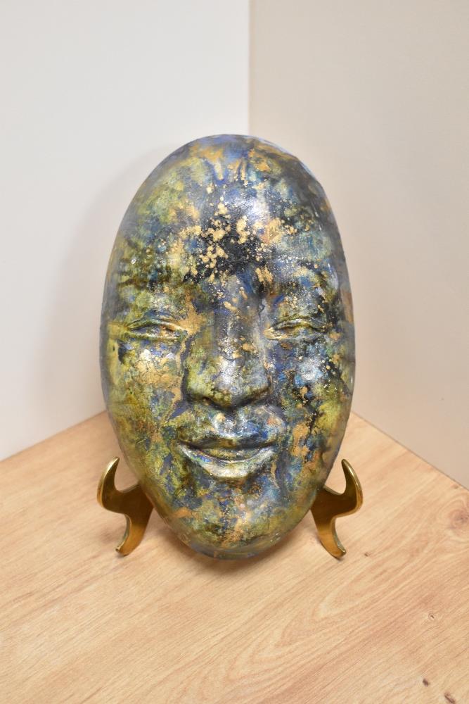 A Chinese pottery hanging wall mask, glazed in a lustre palette of green and blue, measuring 24cm