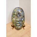 A Chinese pottery hanging wall mask, glazed in a lustre palette of green and blue, measuring 24cm