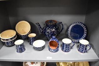 An assorted collection of Wetheriggs Penrith pottery, slip glazed, against a blue ground, and