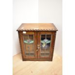 A late 19th Century oak smoker's cabinet, with leaded and stained glass panelled doors, having a
