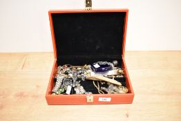 A red leather jewellery box containing assorted jewellery, to include a filigree flower brooch, an