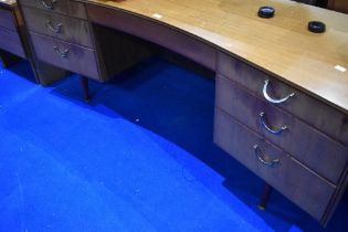 A vintage teak dressing table of curved form, width approx. 163cm, mirrors have been removed but are