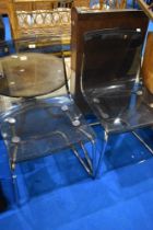 A pair of vintage chrome frame dining chairs with smokey perspex seats