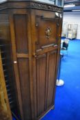 An early 20th Century oak canted hall robe with linen fold decoration to lower door panels ,