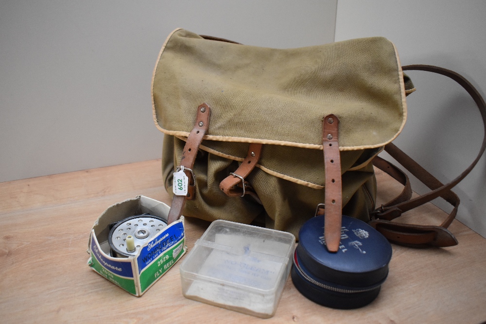 A canvas fishing bag in olive green containing two fly reels by shakespeare...