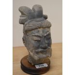 A cast terracotta Chinese warrior head on wood plinth.