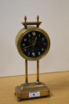 An early 20th Century British made gravity clock, the brass frame holding the weighted circular