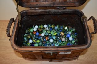A rattan lidded basket housing a large quantity of marbles.