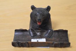 A Black Forest carved bear inkwell and pen stand, measuring 7cm high and 14cm long