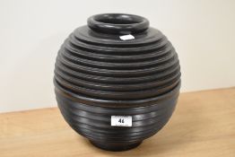 An ebonised wooden vase, of ribbed and spherical form, measuring 25cm tall