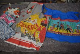 Five vintage aprons, including novelty print half apron and bright floral aprons.