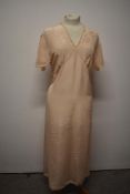 A 1930s / 1940s peach nightdress with lace and appliqué detail to bodice and tie fastening to waist,