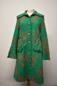 An Arteliers Rare Toggery coat in green linen fabrics with orange floral embroidery.