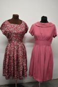Two vintage 1950s dresses, one textured medium weight fabric in rose pink and the other cerise