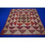 A 19th century patchwork coverlet, using floral, red, black and beige fabrics, having natural cotton