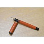 A Parker Lady Duofold Lucky Curve button fill fountain pen in red with broad band to a ring cap