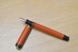 A Parker Lady Duofold Lucky Curve button fill fountain pen in red with broad band to a ring cap