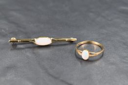 A small 9ct gold ring having a small oval opal in a collared mount to split shoulders on a 9ct