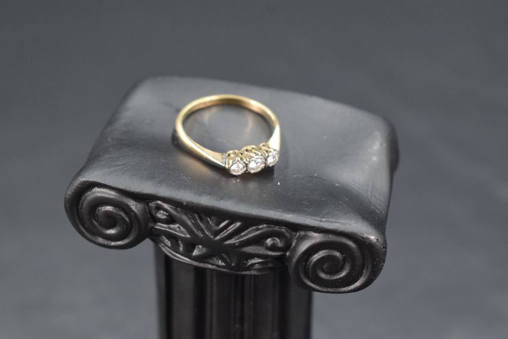 A diamond trilogy ring having three small diamonds in an illusionary mount on an 18ct gold loop,