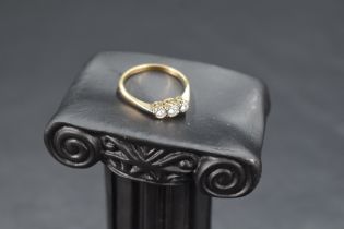 A diamond trilogy ring having three small diamonds in an illusionary mount on an 18ct gold loop,