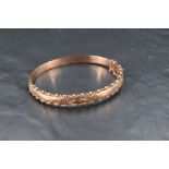A Victorian 9ct rose gold hinged bangle having engraved decoration within a ball and wire border and