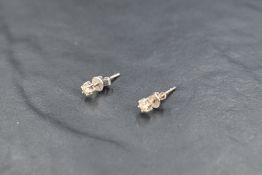 A pair of diamond solitaire stud earrings, each approx 0.064ct in white metal mounts, no marks