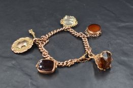 A 9ct rose gold curb link bracelet having four fob charms (one AF), a key charm and a medallion,