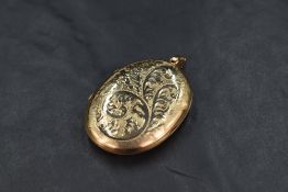 A large 9ct gold locket of oval form having engraved decoration, missing inner lining, approx 12.2g