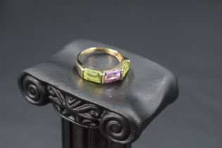 A 9ct gold band ring having a central amethyst flanked by two peridots, size N & approx 3.2g