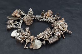 A white metal charm bracelet having padlock clasp stamped silver and twenty eight charms including