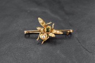 A yellow metal bar brooch bearing a central insect having seed pearl and peridot decoration, missing