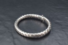 A 9ct white gold woven foil bangle of flexible form having concealed tonge and box clasp, approx